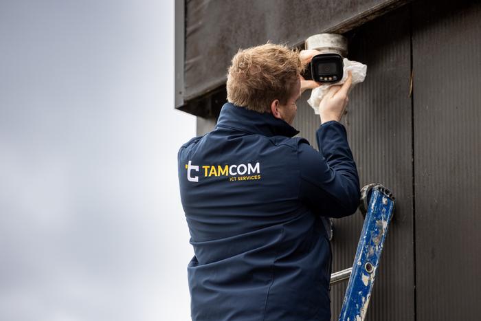 Monteur hangt een camera op aan de stal